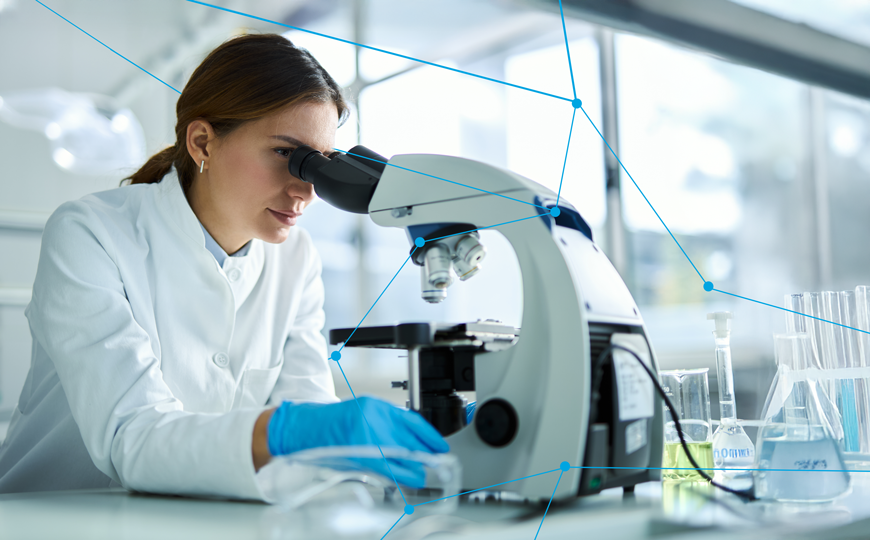 Junge Wissenschaftlerin im weißen Kittel arbeitet im Labor mit einem Mikroskop; im Hintergrund Laborgeräte, Reagenzgläser und eine vernetzte Grafik mit blauen Punkten symbolisiert IoT-Verbindungen.